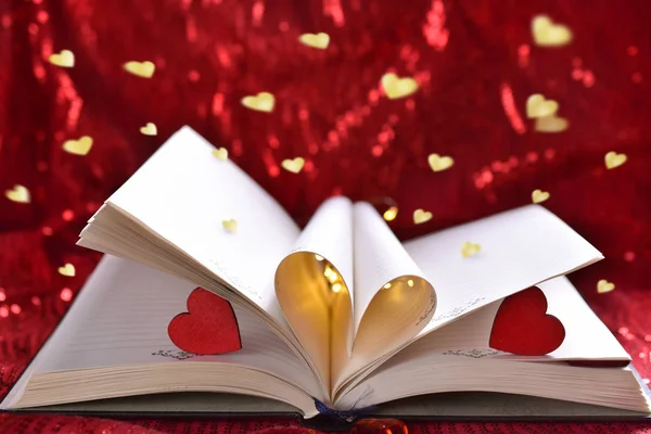 打开的书与心脏形状形式板料在红色背景为情人节的爱概念 — 图库照片