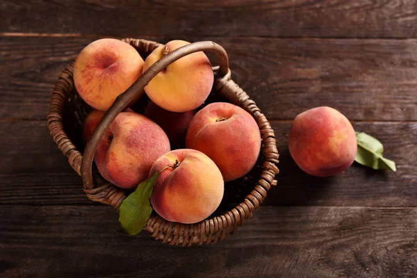 Fresh ripe peaches in a wicker basket — Stock Photo, Image