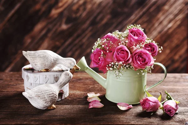 木製のテーブルの上に水やり缶のピンクのバラの束 — ストック写真
