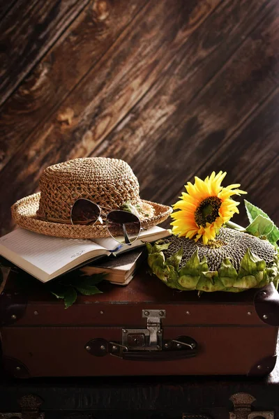 田舎の夏はまだ生きてる古いスーツケースの上に種が横たわるわらの帽子本とひまわり — ストック写真