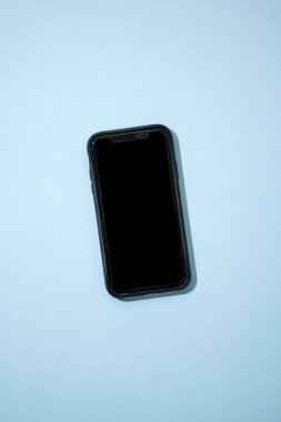 Kulaklıklı bir cep telefonunun stüdyo fotoğrafı.