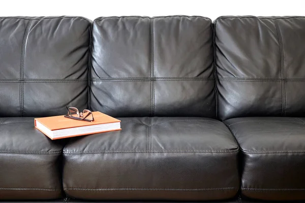 A studio photo of a black leather couch