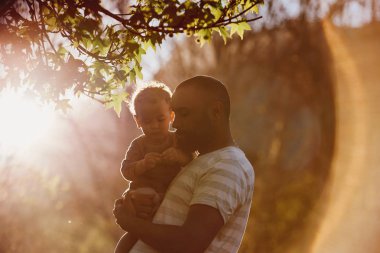 Bir park, küçük oğlu ihale an sevgi dolu taşıyan karma yarış baba