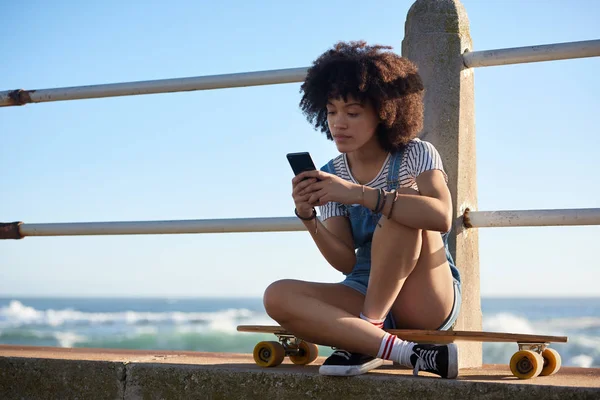 Longboard chica mensajes de texto en el teléfono móvil — Foto de Stock