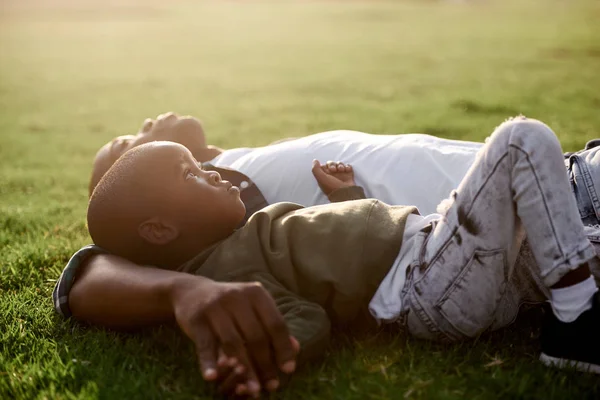 Мальчик, лежащий на траве с отцом — стоковое фото