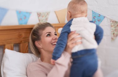 Gülerek oynayan bebek taşıyan güzel anne 