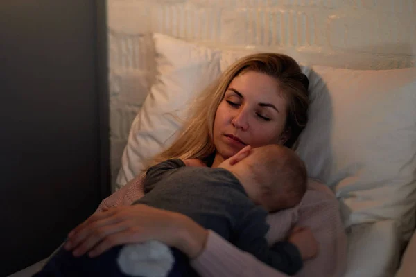 赤ちゃんが彼女の上に眠っている間、疲れた母親の昼寝 — ストック写真