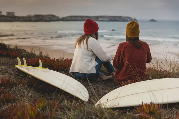 サーフボードで海を見ながら海岸線近く座って二人の親友 — ストック写真