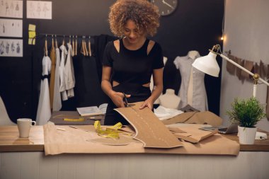 Atölyesinde çalışan genç bir moda tasarımcısı.