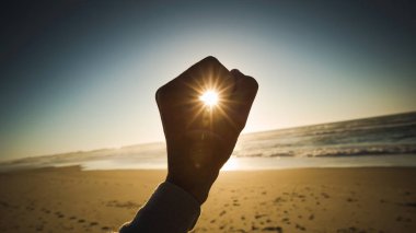 Female hand holding the sun on a signal of hope and strength clipart