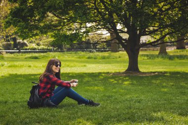 Beautiful woman sitting on rhe grass and relaxing  clipart