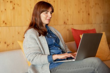 Rahat bir yerde dizüstü bilgisayarda çalışan bir kadın.