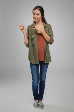 Stüdyoda kendine güveni tam genç bir kadın, sol tarafı işaret ediyor.