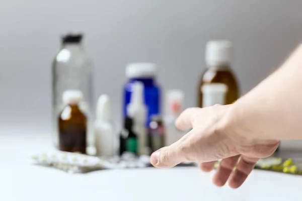 Right hand reaching for meds with selective focus and shallow depth of field. Subjective first person view.