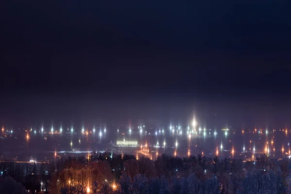 Night winter cityscape with light pillars atmospheric phenomenon — Stock Photo, Image