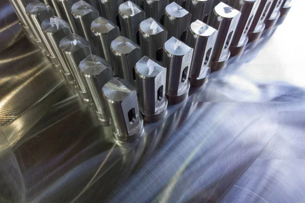 Batch of shiny metal parts after cnc turning and milling on flat milled surface with selective focus. — Stock Photo, Image