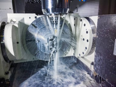 5-axis cnc milling machine at work with coolant under pressure and motion blur of streams.. clipart