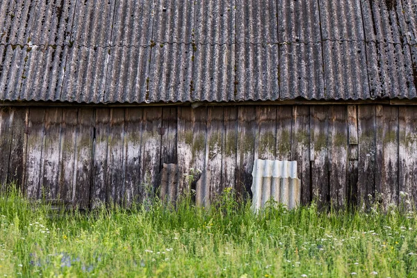 Παλιό τοίχο αχυρώνα με στέγη, πράσινο γρασίδι και επιλεκτική εστίαση θόλωση στο καλοκαίρι της ημέρας — Φωτογραφία Αρχείου