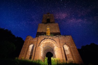 yıldızlı gece ormanda gece çan kulesi harabe ve altında el feneri ile adam