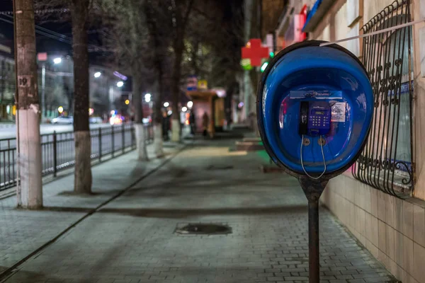 TULA, RUSIA - 22 DE ABRIL DE 2017: teléfono público azul en la acera de la ciudad nocturna con enfoque selectivo — Foto de Stock