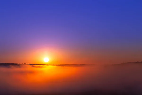 Золотисто-голубой летний восход солнца над туманом без облаков в минималистской композиции — стоковое фото