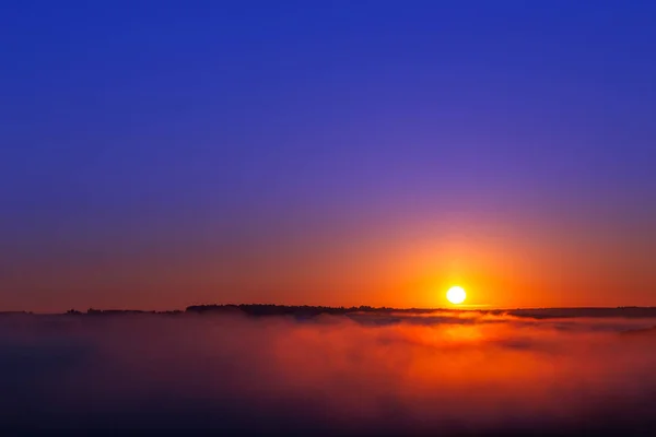 golden-blue summer sunrise over fog without clouds in minimalistic composition