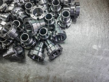 Seçici odaklı çelik yüzeyde cnc tornalama, delme ve işleme sonrası parlak çelik parçalar.