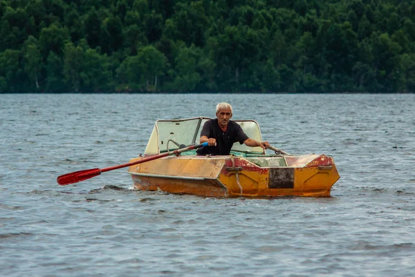 REPUBBLICA DI KARELIA, RUSSIA - 2 LUGLIO 2013: Vecchio abbronzato dai capelli grigi che naviga in barca con pagaie sul lago di Carelia . — Foto Stock