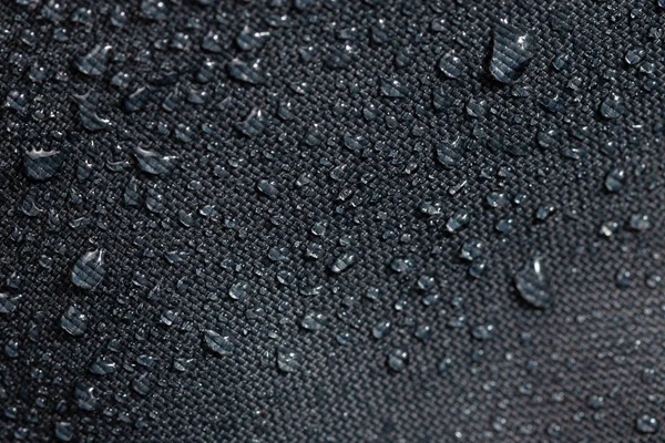 Donker grijze waterdichte hydrofobe doek close-up met water druppels selectieve focus achtergrond — Stockfoto