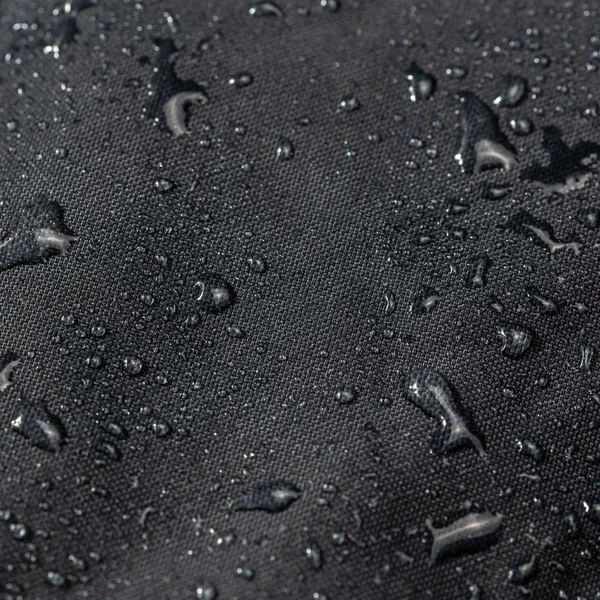 Pano hidrofóbico impermeável cinza escuro close-up com gotas de água foco seletivo fundo — Fotografia de Stock