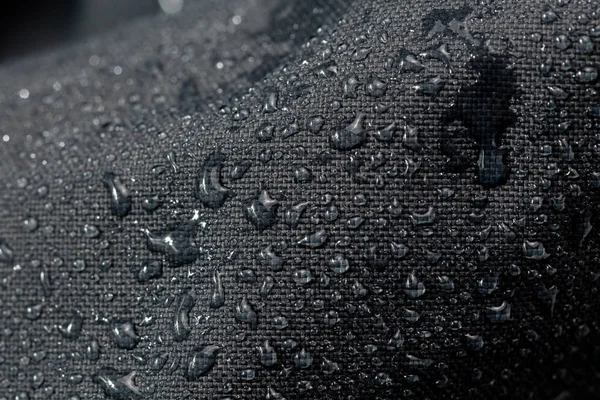 Σκούρο γκρι αδιάβροχο υδρόφοβο πανί κοντινό με νερό σταγόνες επιλεκτική εστίαση φόντο — Φωτογραφία Αρχείου