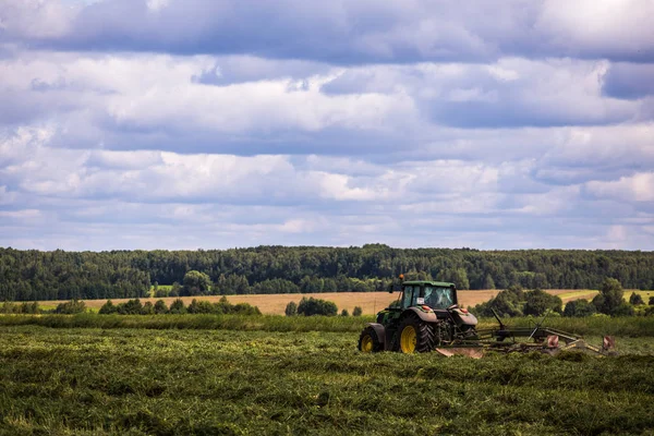TULA, RUSIA - 30 DE JULIO DE 2019: tractor de heno verde en el campo de verano antes de la tormenta - teleobjetivo disparado con enfoque selectivo —  Fotos de Stock
