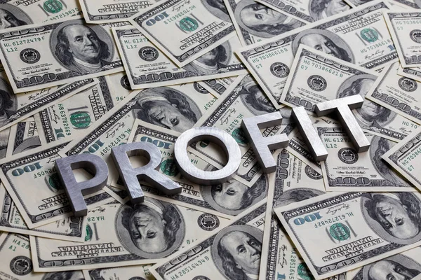 La palabra PROFIT se colocó con letras de aluminio sobre el fondo de los billetes en dólares estadounidenses - con enfoque selectivo — Foto de Stock