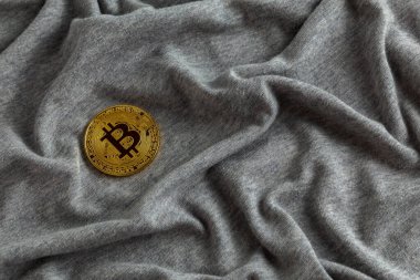 Gri buruşuk pamuk kumaş üzerinde altın bitcoin parlaklığı