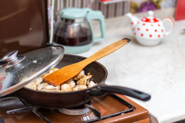 Ayam goreng di panci terbuka dengan lada hitam tanah dan spatula dapur kayu — Stok Foto