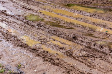 Kirli çamur yolu su birikintileri ve lastik izleri ile - seçici odaklı yakın plan, çapraz kompozisyon