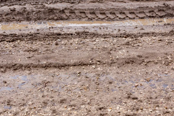 Estrada de barro sujo com poças e faixas de pneus - close-up com foco seletivo — Fotografia de Stock