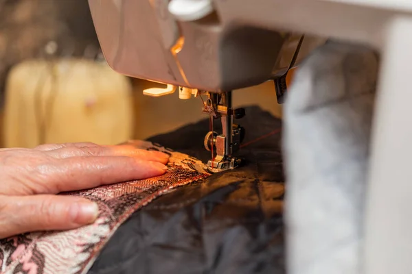 Крупним планом вид швейного процесу, рука старої жінки з використанням швейної машини, методика вибіркового фокусування — стокове фото