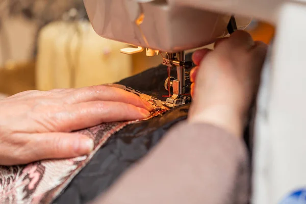 Una vista de cerca del proceso de costura, mano de la anciana utilizando la máquina de coser, técnica de enfoque selectivo — Foto de Stock