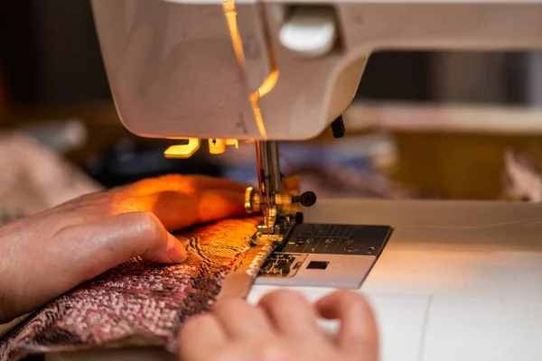 Крупним планом вид швейного процесу, рука старої жінки з використанням швейної машини, методика вибіркового фокусування — стокове фото