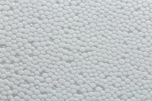 Simple close-up flat but bumpy background of white polystyrene foam or styrofoam, white on white backdrop with selective focus and partial blur. — Stock Photo, Image