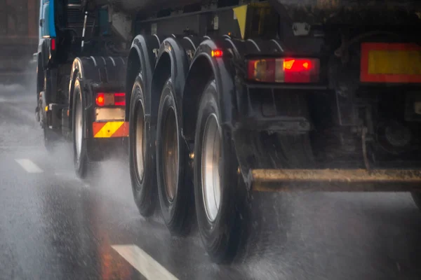 Regen water spatten stroom van wielen van zware vrachtwagen snel in daglicht stad met selectieve focus. — Stockfoto