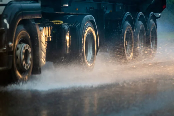 Поток дождевой воды из колес тяжелого грузовика, быстро движущегося в дневном городе с избирательным фокусом . — стоковое фото