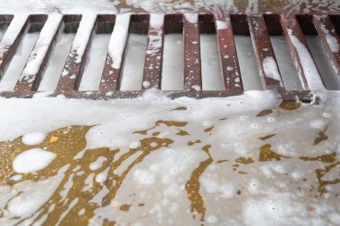 Araba yıkama garajında sabun köpüğü atığıyla yer döşemesi. Seçici odaklı tam çerçeve yakın çekim.