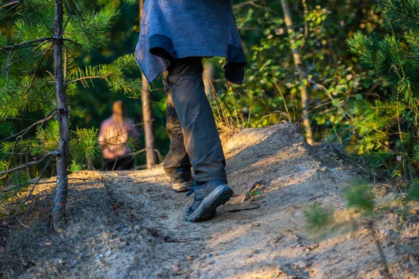 Πεζοπορία πόδια άνθρωπος με παπούτσια και παντελόνι κάπου στο δάσος καλοκαίρι, γκρο πλαν με επιλεκτική εστίαση. Θολή σιλουέτα κοριτσιού στο παρασκήνιο. — Φωτογραφία Αρχείου