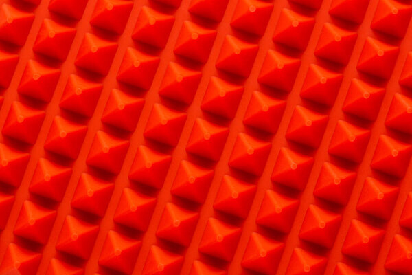 Abstract red silicone pyramids array close-up background.