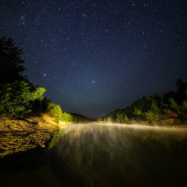 Маленькое озеро под звездами ночью с туманным паром летом — стоковое фото