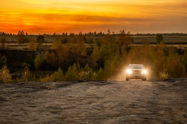 VOLKOVO, RUSSIA - PAŹDZIERNIK 10, 2020: Niebieski Nissan Qashqai wspina się po polnej drodze jesienią złoty zachód słońca froad. — Zdjęcie stockowe