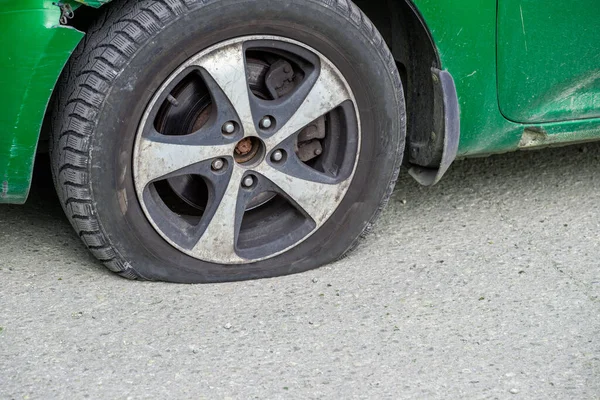 灰色のアスファルト表面上の乾燥晴れた日に古い緑の市民車のフラットタイヤの閉鎖 — ストック写真