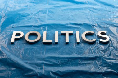 Siyaset sözcüğü, resmin ortasında buruşmuş plastik mavi film arkaplanının üzerine gümüş alüminyum harflerle yazıldı.